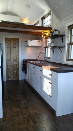 View of kitchen area including wall shelves, and stove with extractor hood.