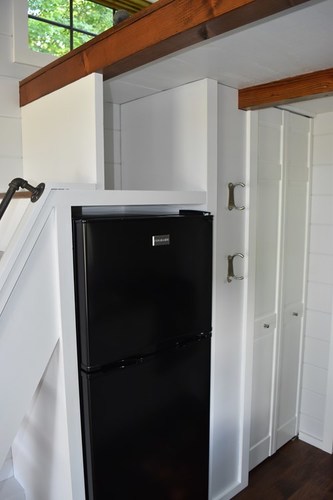 Apartment style fridge/freezer space, stairs going up to loft area and (closed) pantry door.
