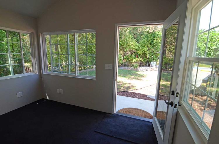 Internal view of a backyard office with light-color painted walls and carpeted floors, from Tuff Shed.