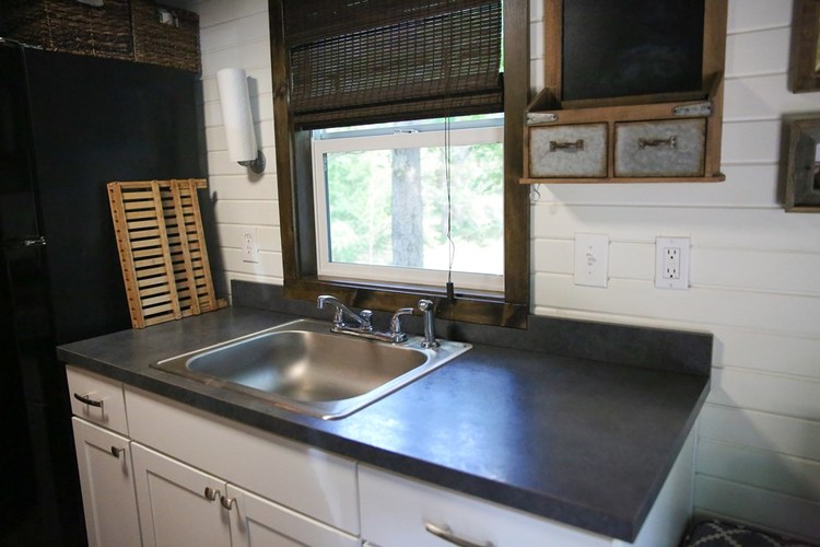 Kitchen worktop and sink, along with further wall mounted storage. Also has a window with views to the outside.